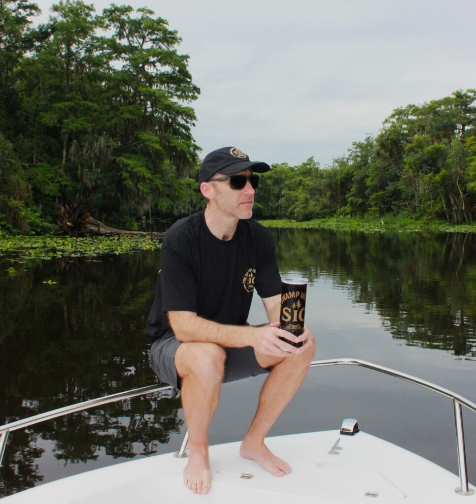 Person holding SIC Signature 20oz Skinny Tumbler while seated on a boat