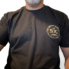 Person wearing black Built for the Grit T-Shirt with circular SIC chest logo